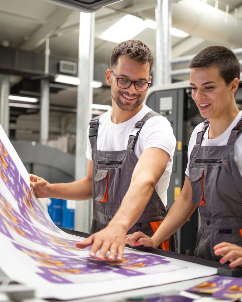 Graphic engineers or workers checking imprint quality in modern print shop.